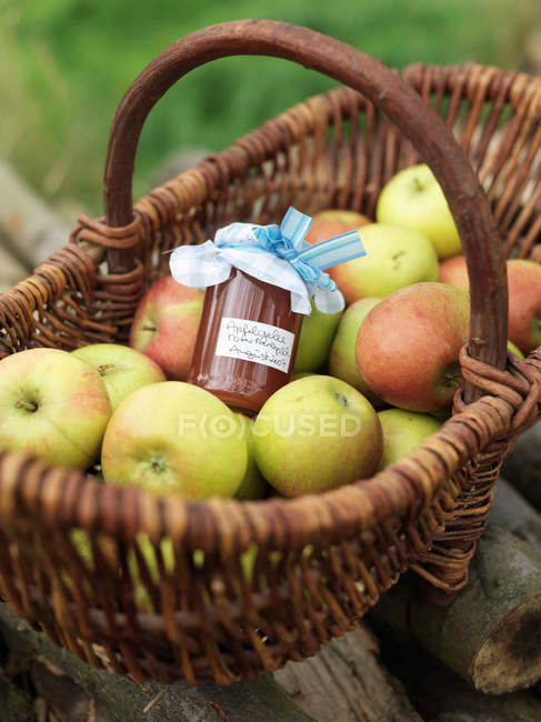 Manzanas en cesta con tarro de mermelada de manzana - foto de stock