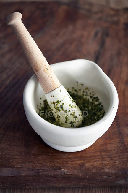 Pestle and mortar with pesto on wooden table — Stock Photo