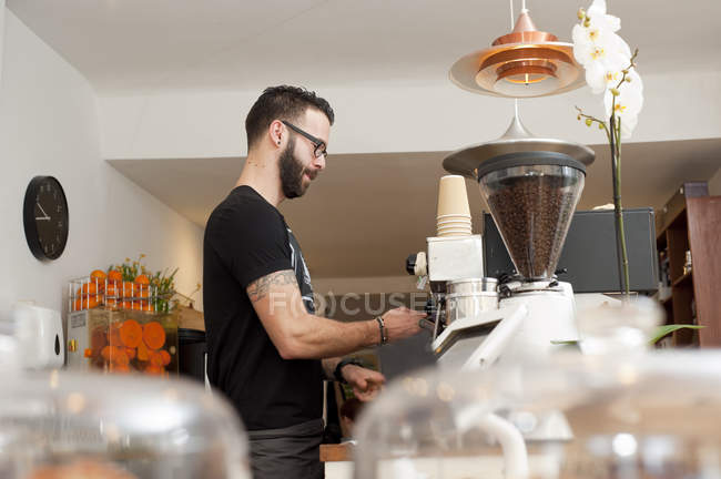 Café camarero preparando café fresco detrás del mostrador - foto de stock