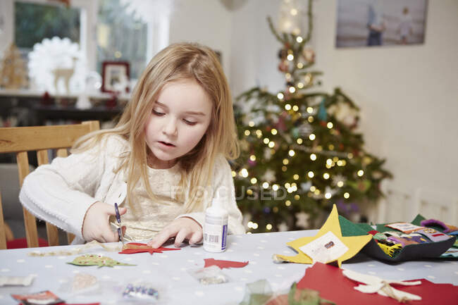 Menina cortando papel preparando-se para o Natal — Fotografia de Stock