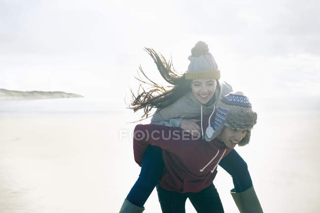 Людина, даючи жінці Хрюшка назад, піски Brean Сомерсет — стокове фото