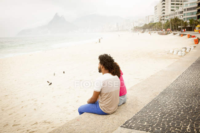 Couple sitting looking out from Ipanema beach, Rio De Janeiro, Brazil — Stock Photo