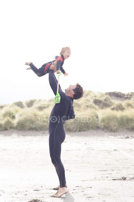 Padre levantando hijo en la playa - foto de stock