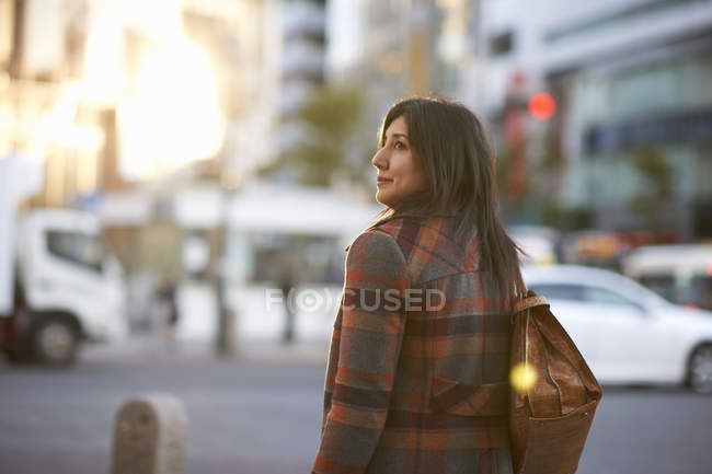 Vista posteriore della donna matura in città che trasporta borsetta a spalla guardando lateralmente, Shibuya, Tokyo, Giappone — Foto stock