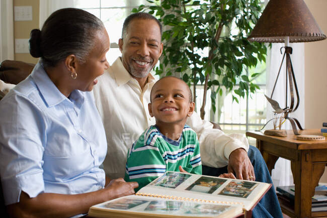 Grandparents and their grandson looking at a photo album — Stock Photo