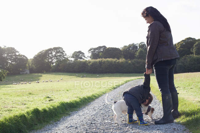 Мати і син ходять собакою по ґрунтовій дорозі — стокове фото