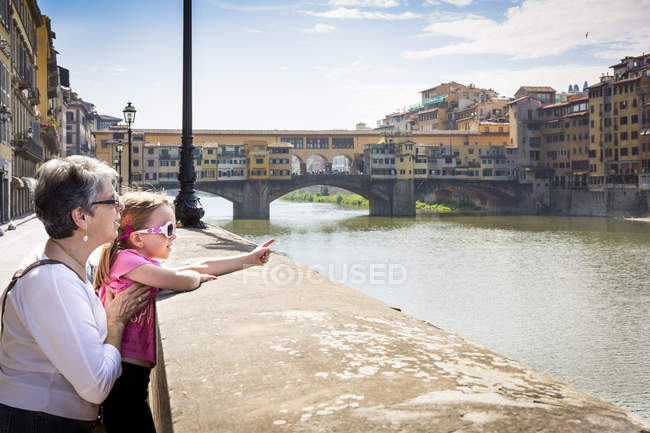 Senior woman and granddaughter pointing at river Arno, Florence, Italy — Stock Photo