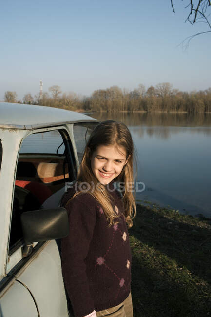 Дівчина стоїть на машині на березі річки — стокове фото
