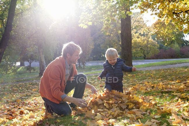 Padre e hijo jugando con hojas de otoño - foto de stock