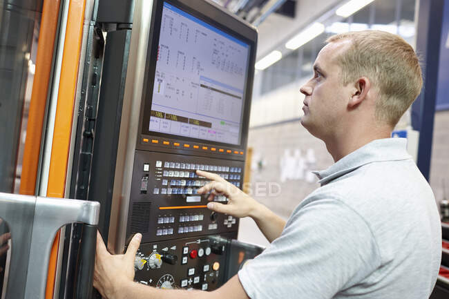 Trabalhador olhando para monitor de computador na fábrica de engenharia — Fotografia de Stock