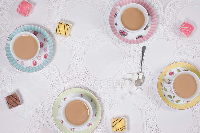 Top view of variety of tea cups and cakes on served table — Stock Photo