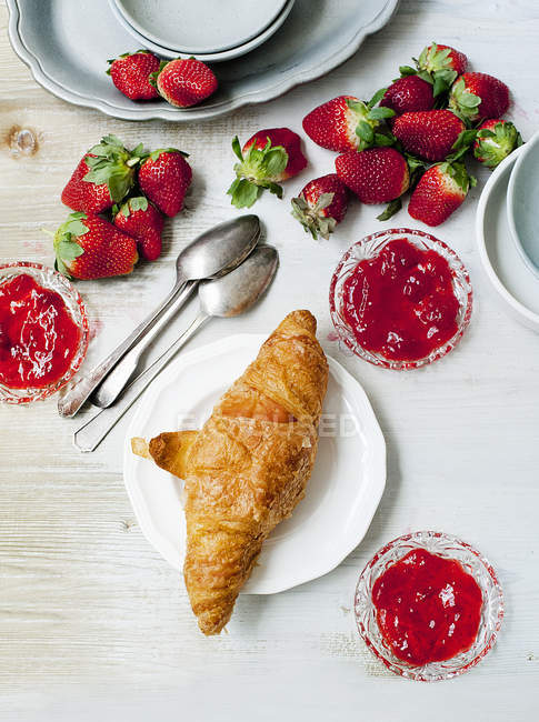 Fresh baked croissant with strawberries and jam — Stock Photo