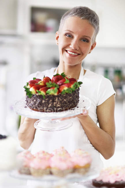 Portrait of woman holding cake with strawberries — Stock Photo