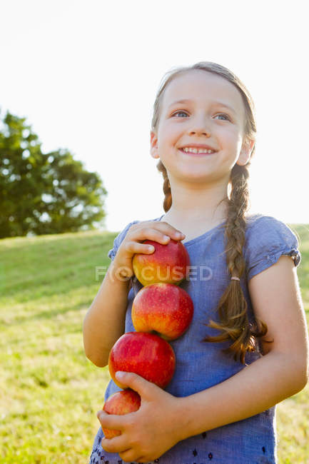 Souriante fille portant des pommes à l'extérieur — Photo de stock