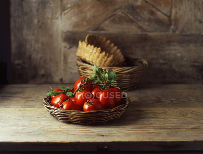 Свежие органические ромовые помидоры в плетеной корзине — стоковое фото