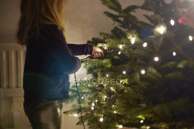 Young girl pulling at christmas lights — Stock Photo