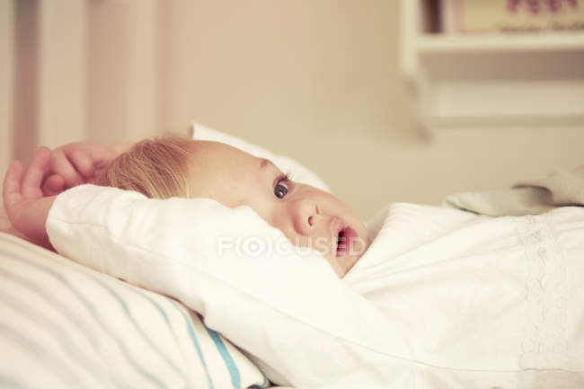 Close up de bebê menina deitada na cama — Fotografia de Stock