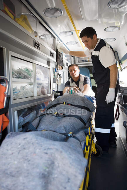 Personal de ambulancia y paciente en camilla - foto de stock