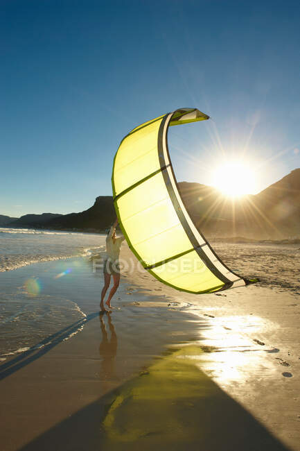 Mujer sosteniendo kitesurf vela en la playa. - foto de stock