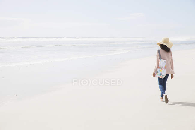 Vue arrière de la jeune femme marchant sur la plage — Photo de stock
