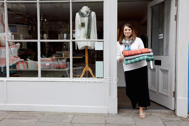 Shop owner in doorway holding fabric — Stock Photo