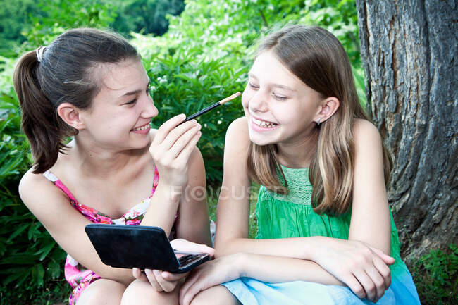 Menina colocando maquiagem na irmã — Fotografia de Stock