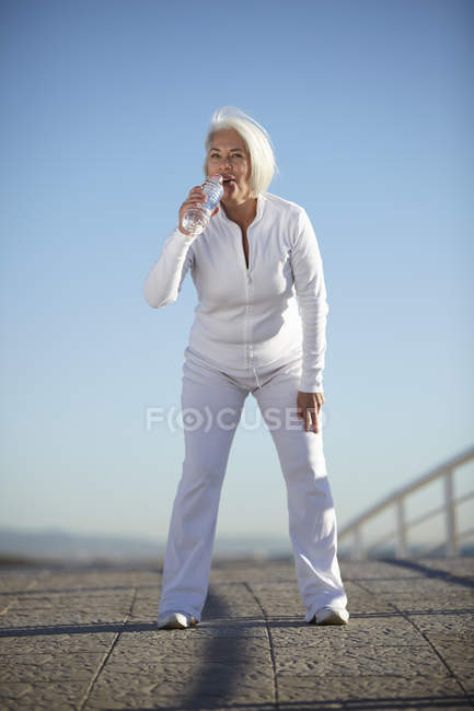 Mature woman drinking water on walk — Stock Photo