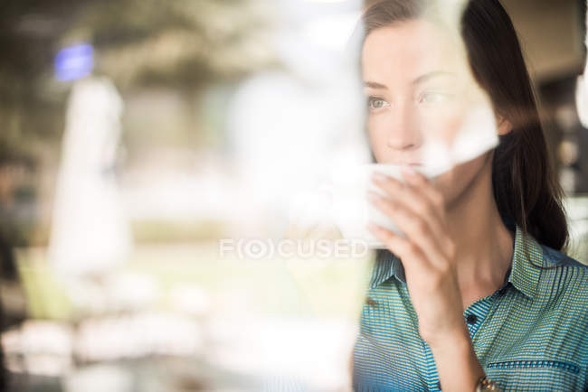 Mulher bebendo café na janela do café reflexivo, Dubai, Emirados Árabes Unidos — Fotografia de Stock