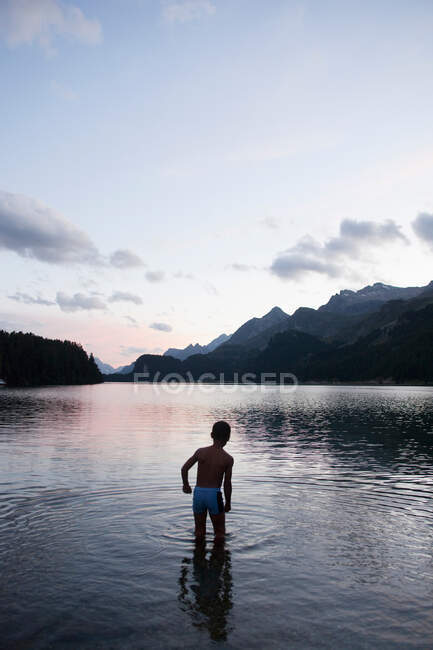 Niño joven bañándose en el lago por la noche - foto de stock