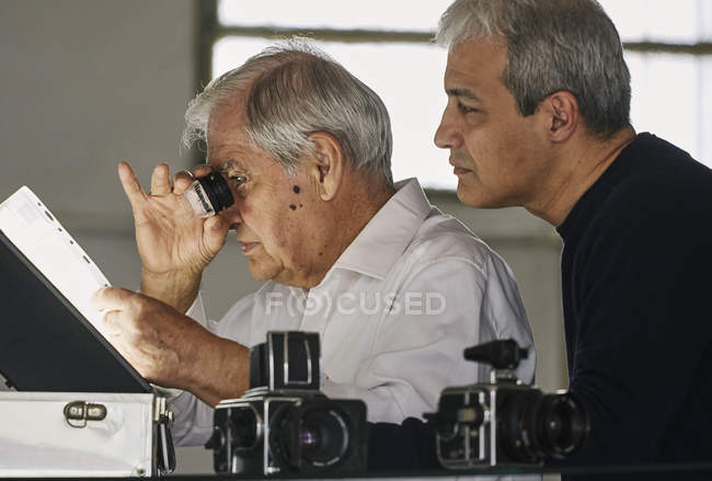 Padre e hijo mirando la hoja de diapositivas de película - foto de stock