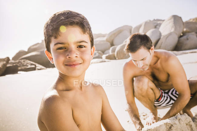 Portrait of boy and father making sandcastle on beach, Cape Town, South Africa — Stock Photo