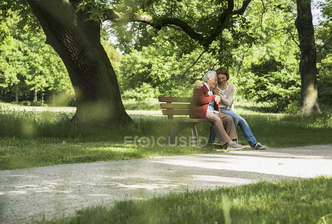 Senior woman sitting on park bench with granddaughter — Stock Photo