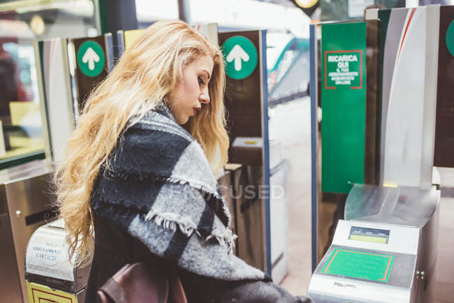 Mujer joven usando la barrera de billetes en la estación de tren - foto de stock