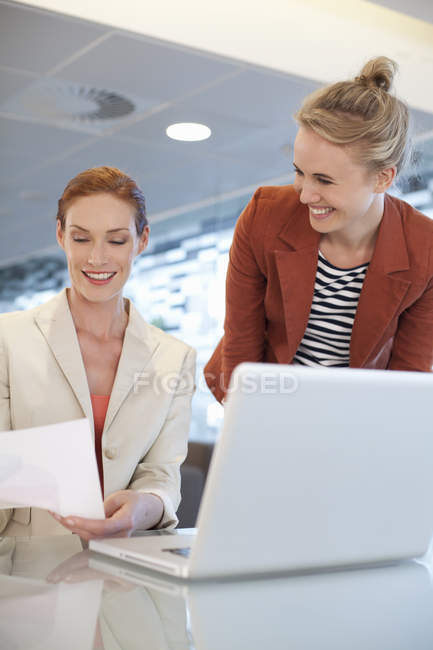 Empresarias sentadas en el escritorio y usando laptop - foto de stock