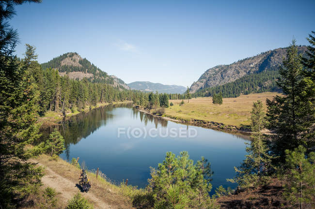 Male cyclist by Kettle Valley River, British Columbia, Canada — Stock Photo