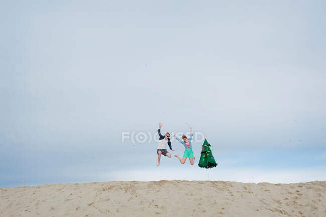 Молодая пара прыгает по пляжу — стоковое фото