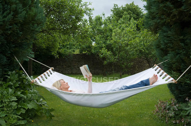 Frau entspannt sich in Hängematte im Garten — Stockfoto