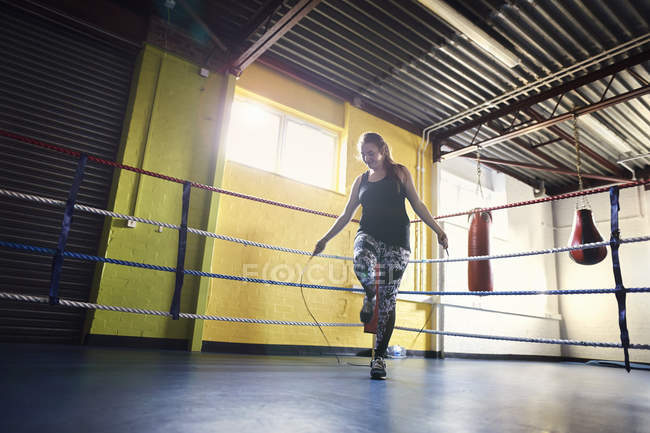 Young female boxer skipping in boxing ring — Stock Photo