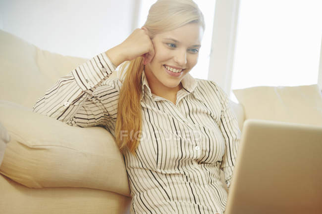 Mujer joven en el sofá, utilizando la tableta digital - foto de stock