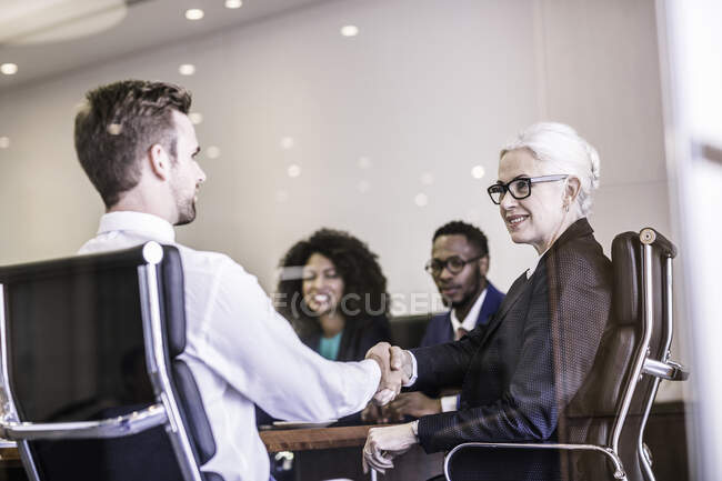 Empresaria y hombre estrechando la mano en la reunión del equipo de la junta directiva - foto de stock