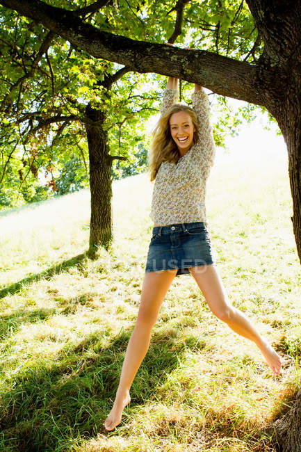Smiling woman hanging from tree — Stock Photo