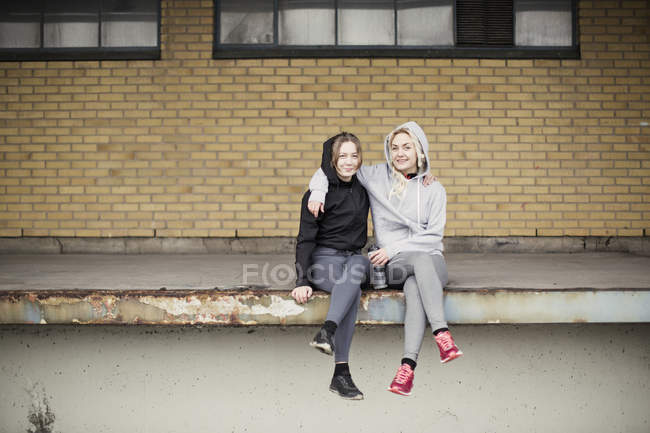 Ritratto di due amiche runner sedute sulla piattaforma del magazzino — Foto stock