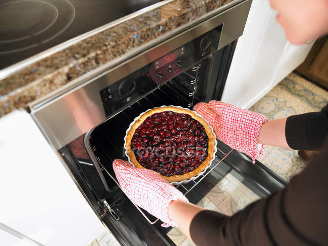 Abgeschnittenes Bild von Kuchen, der von weiblichen Händen aus dem Ofen kommt — Stockfoto