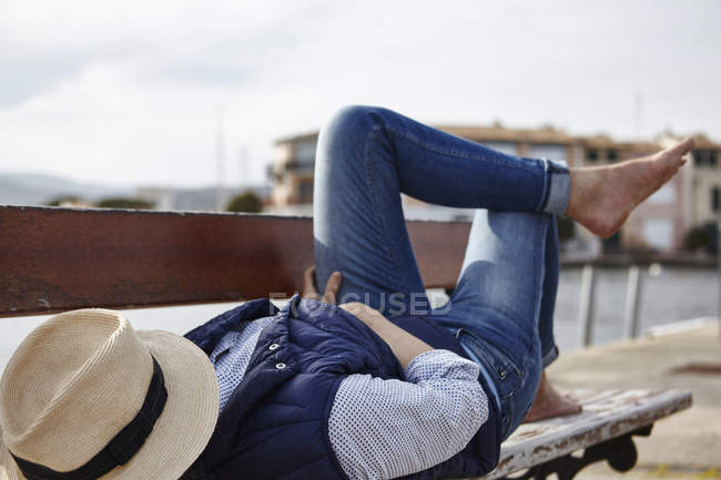 Mature woman lying on bench, hat covering face — Stock Photo