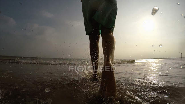 Ноги женщины на береговой линии, идущей в океане — стоковое фото