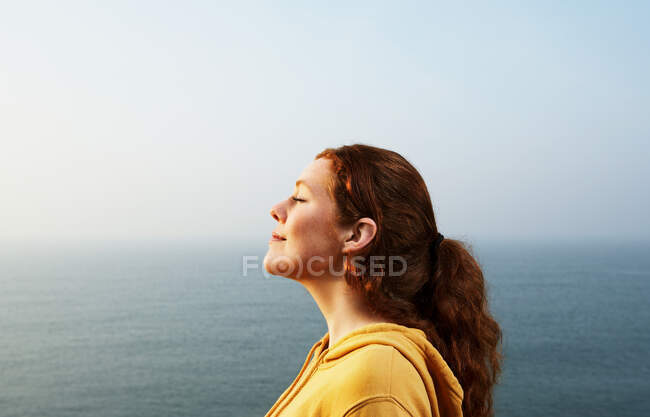Perfil de una joven junto al mar - foto de stock
