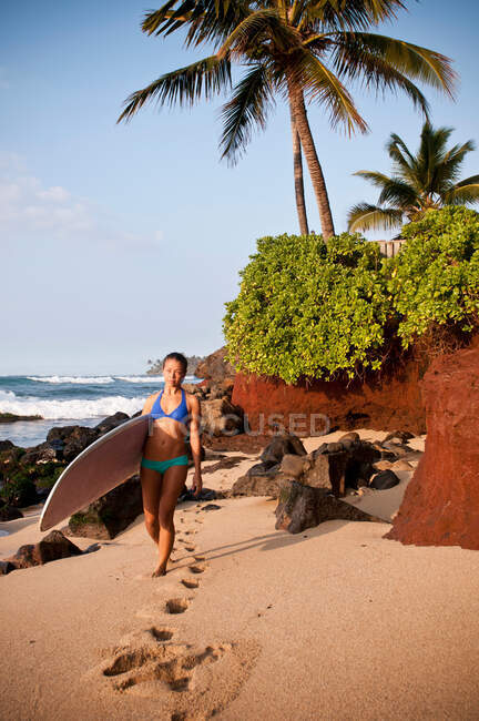 Surfer carrying surfboard on beach — Stock Photo