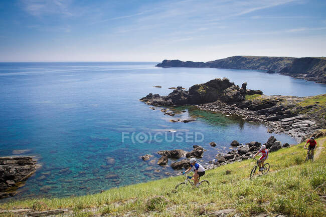 Mountain bikers riding on coastline — Stock Photo