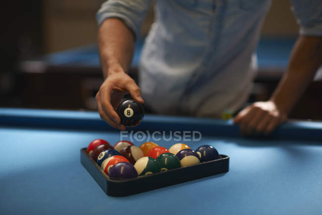 Man arranging balls into triangle on pool table — Stock Photo