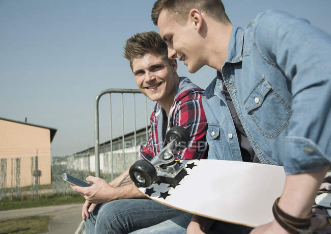 Deux jeunes hommes en skatepark avec smartphone — Photo de stock